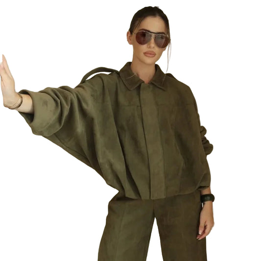 Woman wearing a green outfit with sunglasses on a plain background